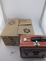 Closed cardboard box labeled 1990 MLB Upper Deck, 1991 Donruss, and baseball cards inside, alongside red Topps collector's tin lunchbox