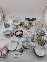 Full view of the lot with bracelets, necklaces, and brooches arranged showing some items sealed in plastic bags and some loose