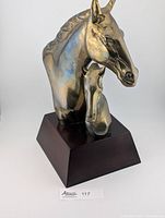 Front view of brass horse and foal heads on wood base showing patina and oxidation