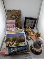 Collection of Egyptian-themed items including brass desk set, books, jewelry, and framed art on a table.