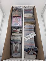 Photo showing divided box with two sections holding large quantity of NBA basketball cards. Section one labeled 'All Rookie Cards & Numbered/Signed'. Section two labeled 'Stars, Inserts, etc.'