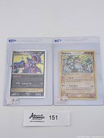 Both cards sleeved and shown front face with price labels and lot number.