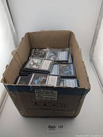 Box containing approximately 1000 blue Magic the Gathering cards sorted by color with some sleeved cards visible on top.