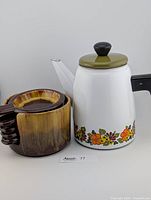 Vintage Austria enamel coffee pot with floral decoration and green lid, black handle and knob.