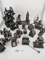Full top-down view of all miniature brass and metal sharpeners arranged over a white surface.