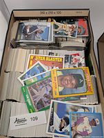 Top view of a large cardboard box tightly packed with over 1200 vintage baseball cards. Visible front cards feature players like Reggie Jackson and Leon Durham from Score brand.