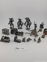 Full lot of pewter miniatures and two painted cast iron figures shown together on white background.