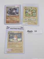 Front photo of three Pokemon holo trading cards in protective sleeves with price tags visible.