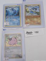 Lot of three Pokemon cards in protective sleeves laid out flat: Vaporeon, Lucario, Cleffa. Each card has price tags. Lucario and Vaporeon cards have yellow borders and clear holo backgrounds. Cleffa card has a white border, also holo. The cards are visible with details including artwork and stats.