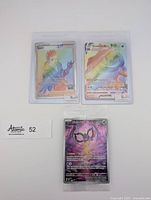 Three Pokémon trading cards displayed: Rainbow Spark Trainer #85, Rainbow Dreadnaw VMax #75, and sealed Pecharunt Promo #129.
