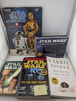 Photo showing all five Star Wars related books, including The Star Wars Storybook 1978 with characters R2-D2 and C-3PO on the cover, Carrie Fisher's Wishful Drinking, and Star Wars Trilogy.