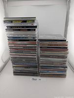 Front view of two stacks of CDs showing spines and titles of various artists.