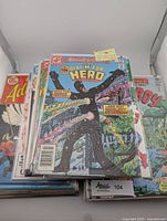 Stack of vintage DC comic books including Aquaman, Adventure Comics (Dial H for Hero), and Superboy, in protective sleeves.