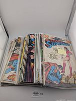 Stack of approximately 30 vintage Superman comic books from the 1970s with visible wear and aged covers featuring Superman in various poses.