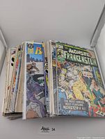 Stack of worn vintage comic books with visible wear and damage, including Monster Frankenstein front cover.