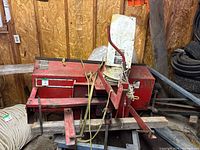 Front and side view of red snow blower housing with mounting arms and brackets