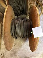 View of assorted spools of steel cable and natural fiber rope on wooden spools, showing thickness and wound condition