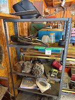 Front view of metal shelving unit with various automotive parts including alternators and belts on shelves.