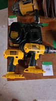 Two yellow DeWalt cordless drills along with two black NiCd battery chargers on a concrete floor.