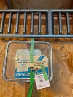 Photo showing metal grill, owner manual, and hub cap taped with lot number.