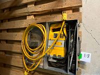 Electric hammer drill, model Kango 400, inside metal carrying case with yellow power cable and secondary cable coiled beside it.