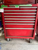 Front view of the red metal rolling tool chest showing nine drawers and caster wheels.