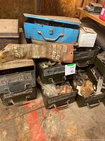 Photo of multiple metal hardware drawers/boxes stacked together with assorted hardware items and a blue toolbox on top. Sketches and labels on drawers visible.