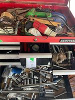 Full view of open red metal toolbox showing top compartment with green glue gun, pipe cutter, tape rolls and wires