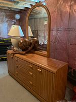 Full view of Palliser wood dresser with attached mirror and decorative lamp on top.