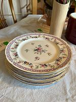 Stack of 8 bone china plates showing floral motif and gold trim Bab pattern around rim