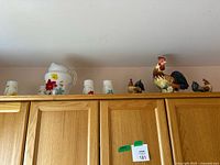 Wide view showing entire lot including glassware and rooster figurines on cabinet top.