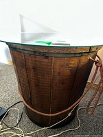 Side view of the wooden barrel table base with the rope detail and partial glass top visible.