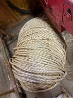 Top-down view of coiled synthetic rope on wooden floor showing full coil and rope texture.