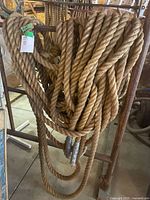 Coil of thick natural fiber rope hanging on a metal frame, showing the rope's size and texture.