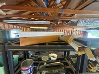 View of variety of tools and wood pieces on black plastic shelf.
