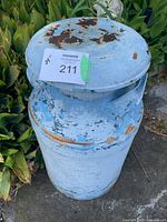 Top angled view of the milk can showing rust and paint chipping on the lid and upper section.
