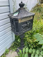 Full view of mailbox and stand leaning against house exterior