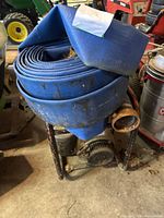 Gasoline powered Wisconsin Robin water pump WI-185 with coiled blue layflat hose on top showing use and dirt.