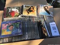Photo showing top view of multiple music CDs in clear jewel cases, including Larry Christmas, Gretchen Wilson, Shania Twain, and Tom Jones.