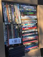 Photo showing multiple DVD cases stacked together, title spines visible including titles like The Exorcism of Emily Rose, Zombieland, and others.
