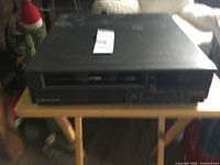 Full view of the Emerson VCR unit placed on a wooden folding table in a room indoor.