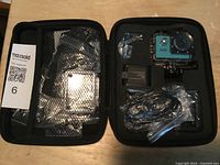 Full view of open carrying case showing HD action camera and accessories inside neatly organized