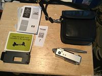 Photo showing HP Photosmart 430 digital camera accessories including user manuals, dock insert, and black camera case with shoulder strap.