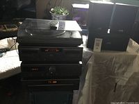 Full setup of JVC sound system with stacked components, four speakers to the side and remote on top of turntable dust cover.