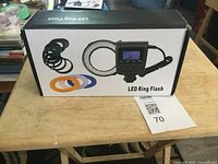 Box of LED ring flash with digital control unit and color filters shown on the table.