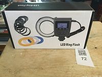 Boxed LED ring flash showing digital control unit, LED ring, multiple mounting rings, and colored diffusers.