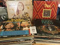 Stack of LP vinyl albums including visible covers of Judy Collins, Poco, Buddy Holly and other assorted records.