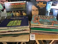 Stacks of LP vinyl albums featuring The Beach Boys Today!, Neil Diamond Collection, The Supremes Greatest Hits and Machine Rock compilation albums on top, showing album covers, condition, and variety.
