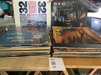 View of stacks of 50 LP vinyl albums including The Beach Boys, REO Speedwagon, Country Superstars compilations, and assorted other vinyl albums in used condition.