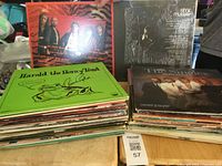 Stack of approximately 50 assorted LP vinyl albums showing three front covers: Harold the Horny Toad, Anne Murray, and The System. Albums appear assorted with various colors and designs typical of used vinyl records.
